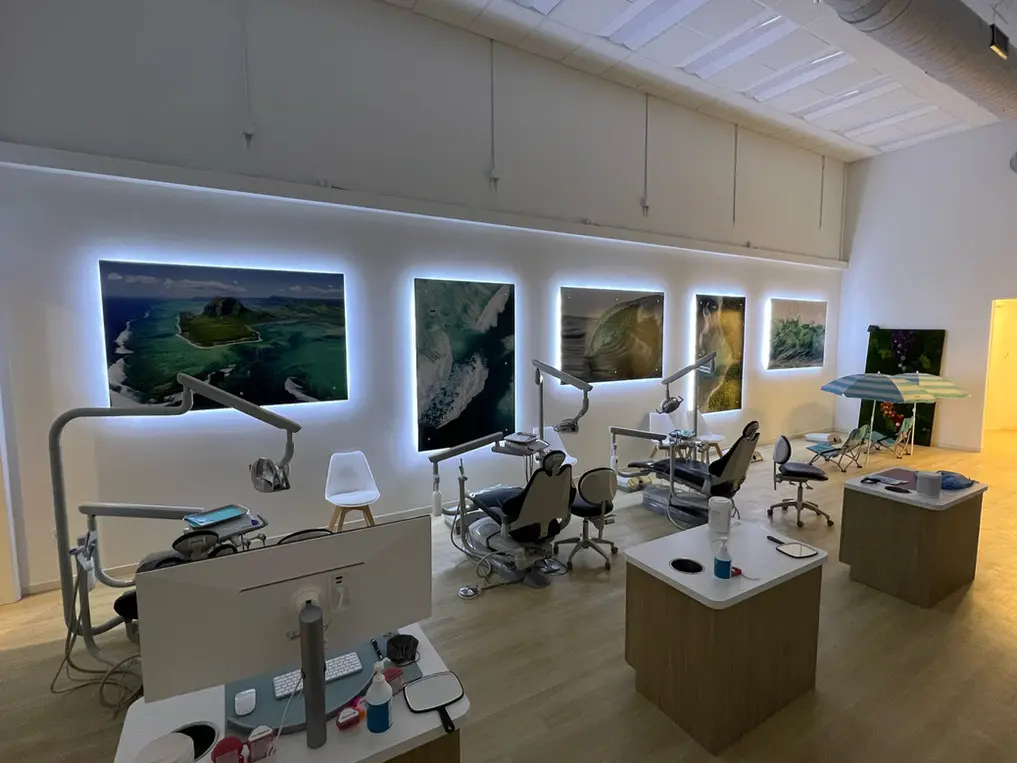 A modern dental clinic, the Bold Bite Orthodontics office in Jacksonville, FL features several dental chairs, advanced equipment, and large illuminated landscape photographs on the wall.