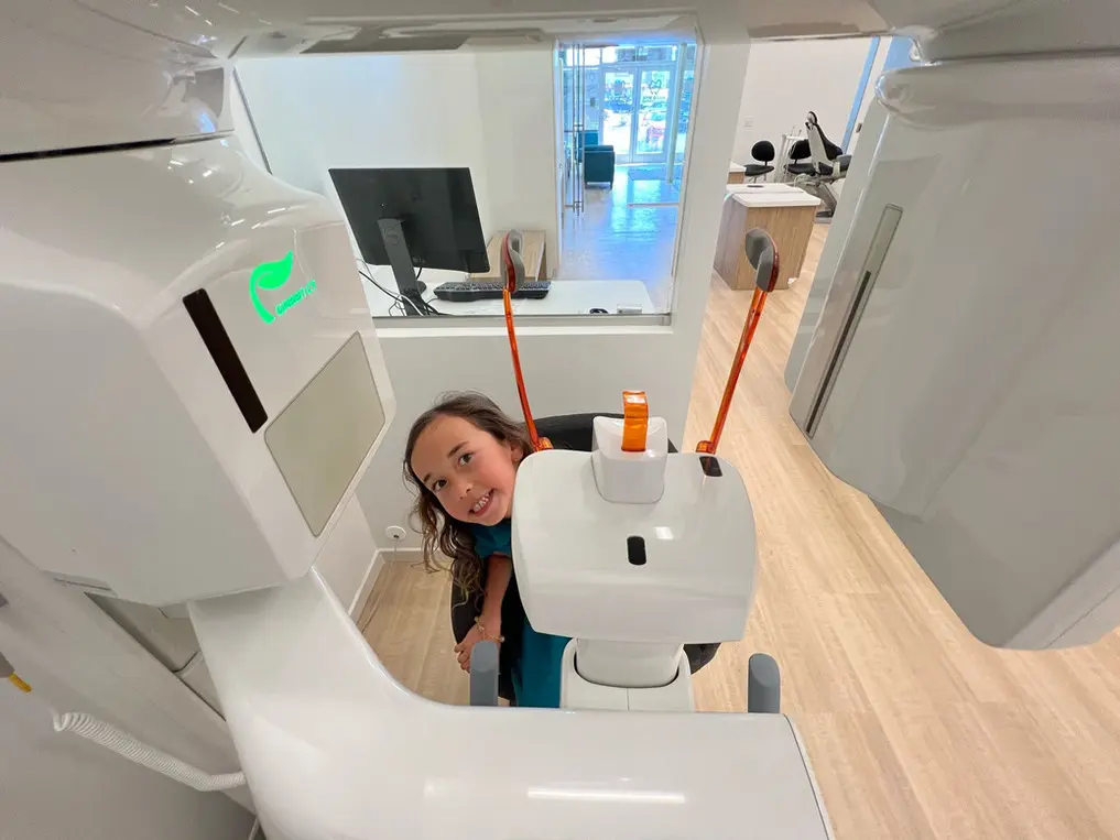 A child stands inside a dental imaging machine at Bold Bite Orthodontics in Jacksonville FL, preparing for a scan in a modern, bright dental office.