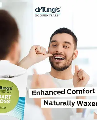 A man flosses his teeth while looking in a mirror. The image features drTung's Smart Floss packaging and text promoting "Enhanced Comfort" and "Naturally Waxed".