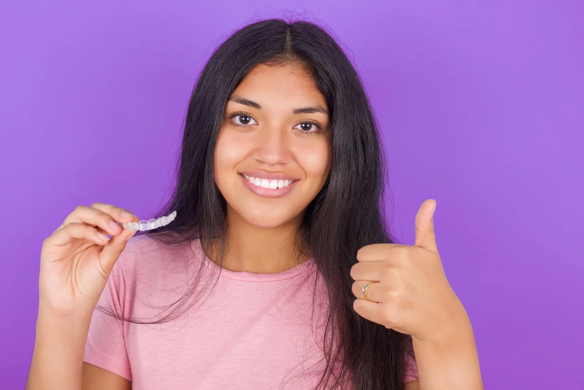 Bold Bite Orthodontics patient holding Invisalign clear aligners