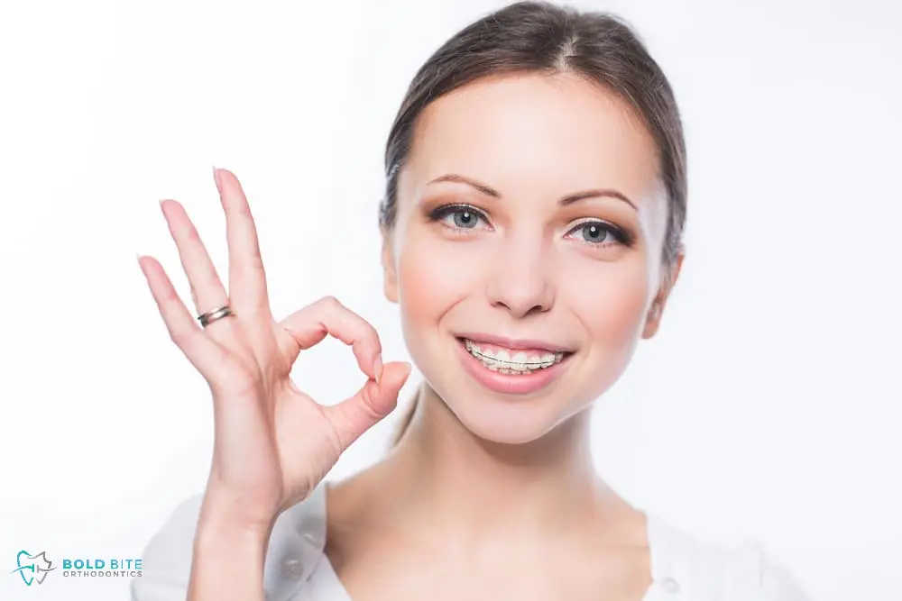 Smiling woman wearing clear ceramic braces, showcasing a discreet orthodontic solution available at Bold Bite Orthodontics in Jacksonville.