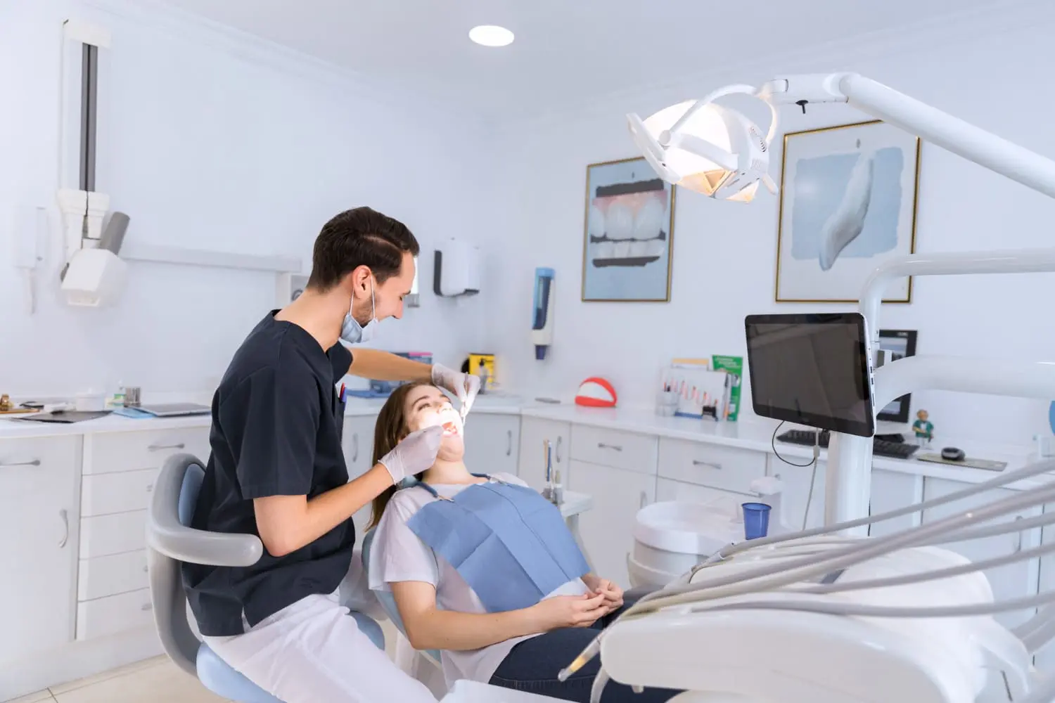 In a well-lit dental office, the dentist carefully examines a patient's teeth, focusing on adult orthodontics. The patient reclines comfortably in the dental chair, surrounded by advanced medical equipment in the background in Jacksonville, FL