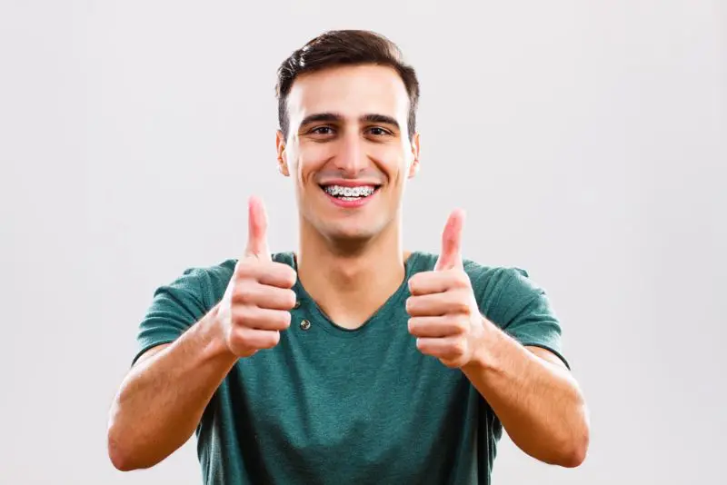 A person wearing a green shirt, smiling with metal braces, and giving two thumbs up in Jacksonville, FL.
