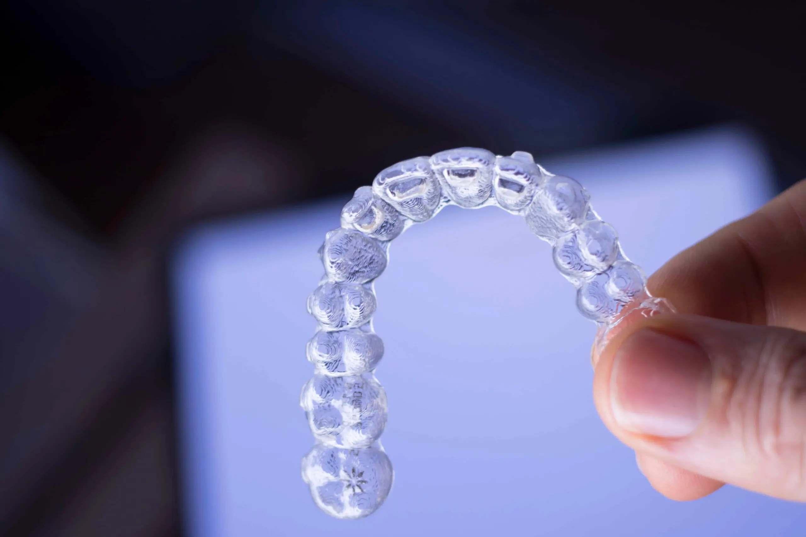 A hand holding a clear dental aligner suggest choose affordable invisalign with invisalign cost  in Jacksonville at Bold Bite Orthodontics in Jacksonville, FL.
