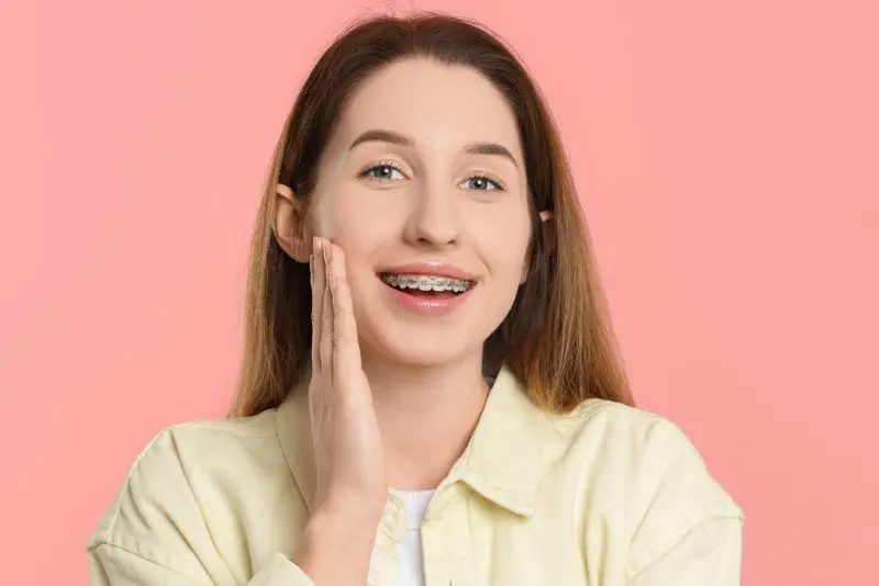 A woman with long hair smiles, showing metal braces, learning about affordable braces cost solutions at Bold Bite Orthodontics in Jacksonville, FL