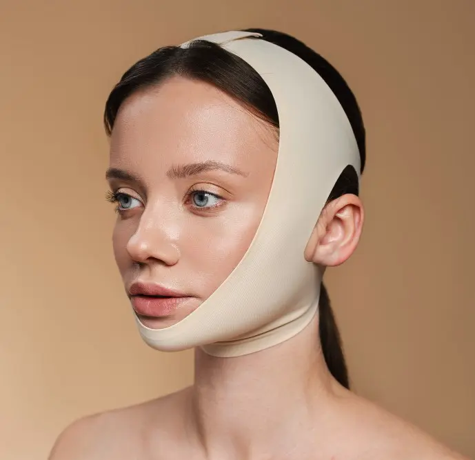 A woman wearing a beige facial compression bandage with a neutral background, likely recovering from jaw surgery in Jacksonville, FL.
