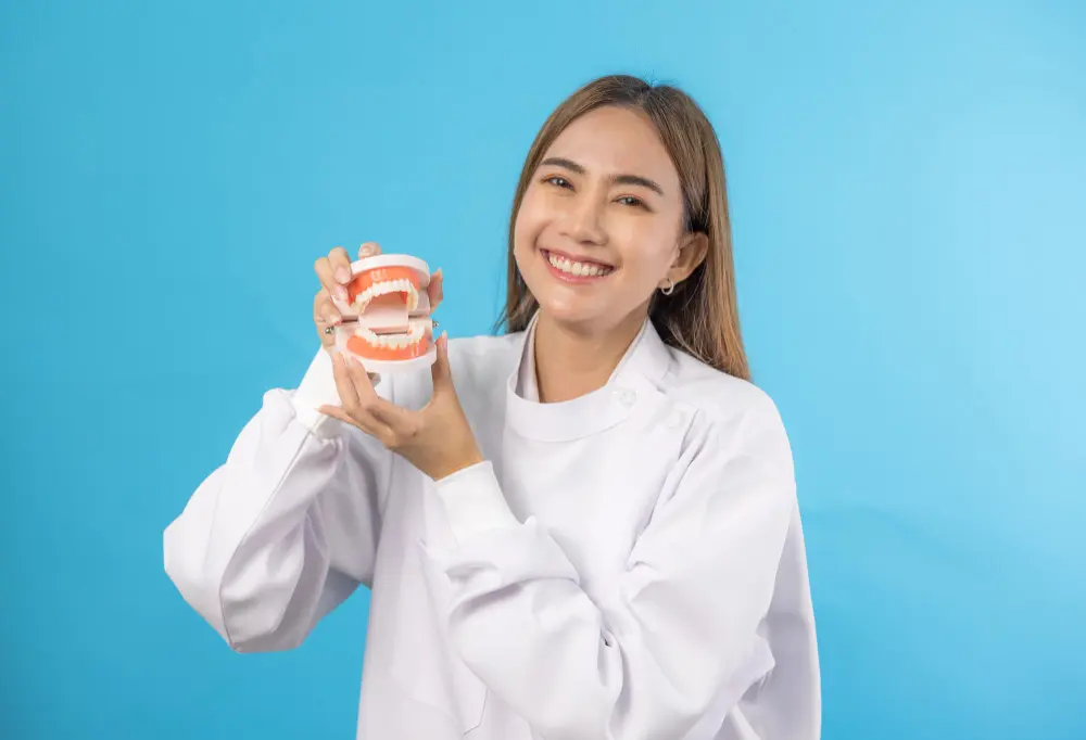 Orthodontic Insurance Plans: A person in a white coat smiles while holding a dental model against a blue background in Jacksonville, FL.