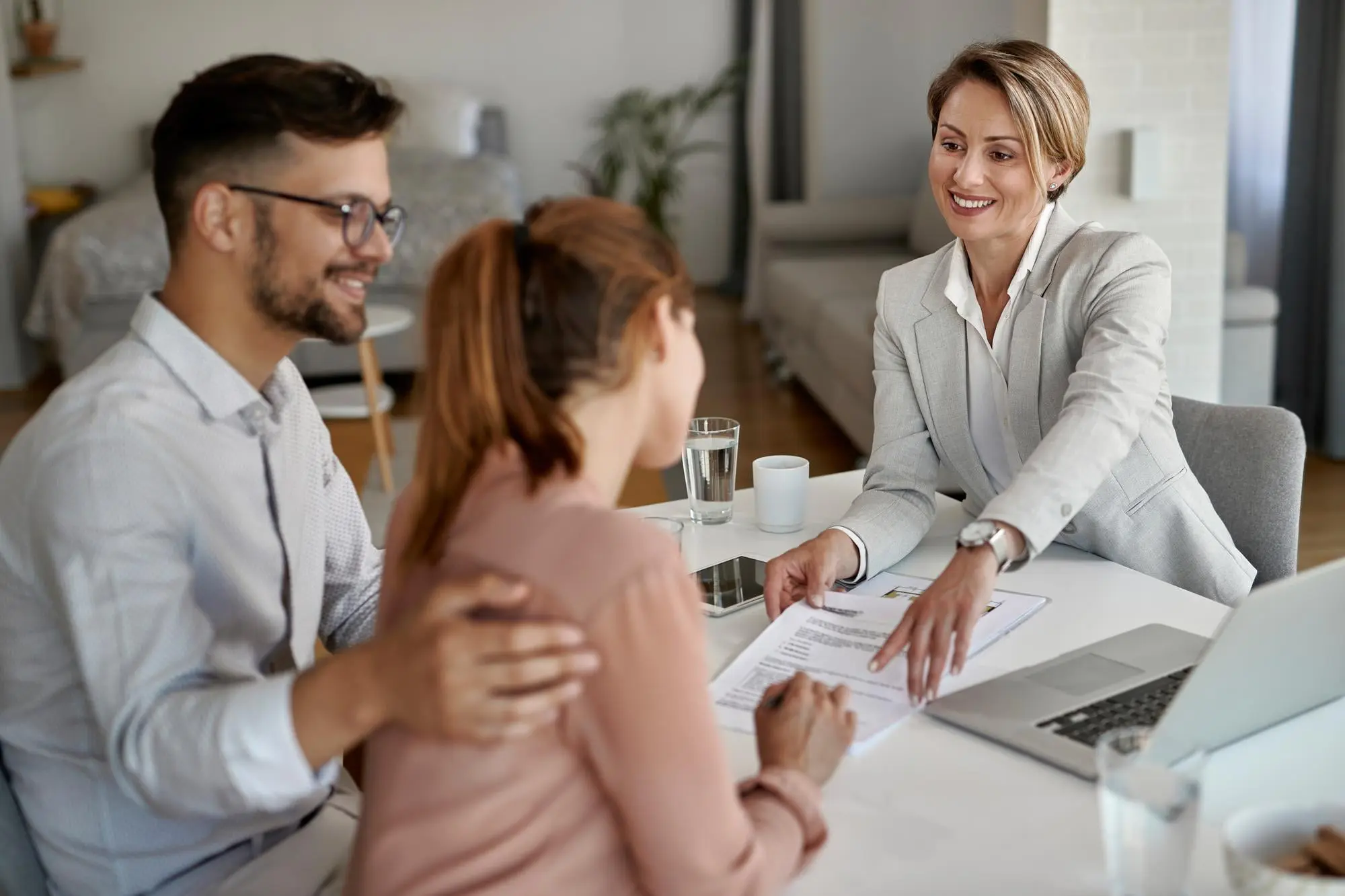 A couple sits at a desk with a professional woman in FL, who is smiling and pointing at a document, suggesting a discussion about dental insurance coverage or an Invisalign payment plan in Jacksonville.
