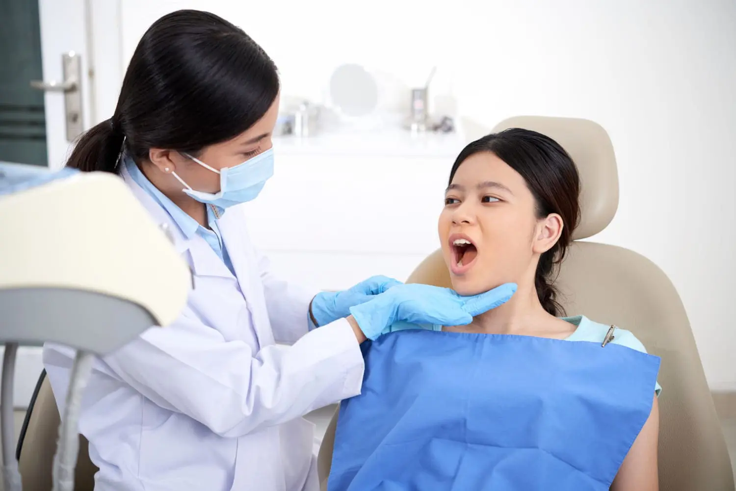 In Jacksonville FL, a dentist wearing a mask and gloves examines a female patient’s open mouth in a dental clinic, evaluating for signs often associated with chronic mouth breathing.