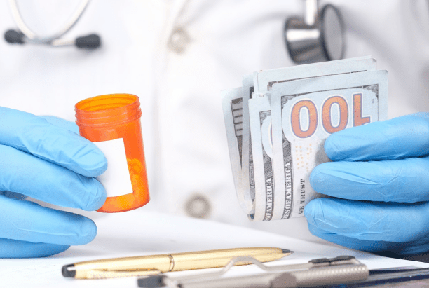 A person in medical attire holds an empty prescription bottle in one hand and a stack of hundred-dollar bills in the other, highlighting the costs tied to dental insurance coverage or an Invisalign payment plan in Jacksonville, FL.