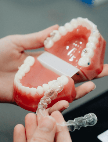 A person holds a dental model of teeth and positions a clear orthodontic aligner in front of it in Jacksonville, FL. Learn about our Invisalign payment plan options to make your smile transformation more affordable.