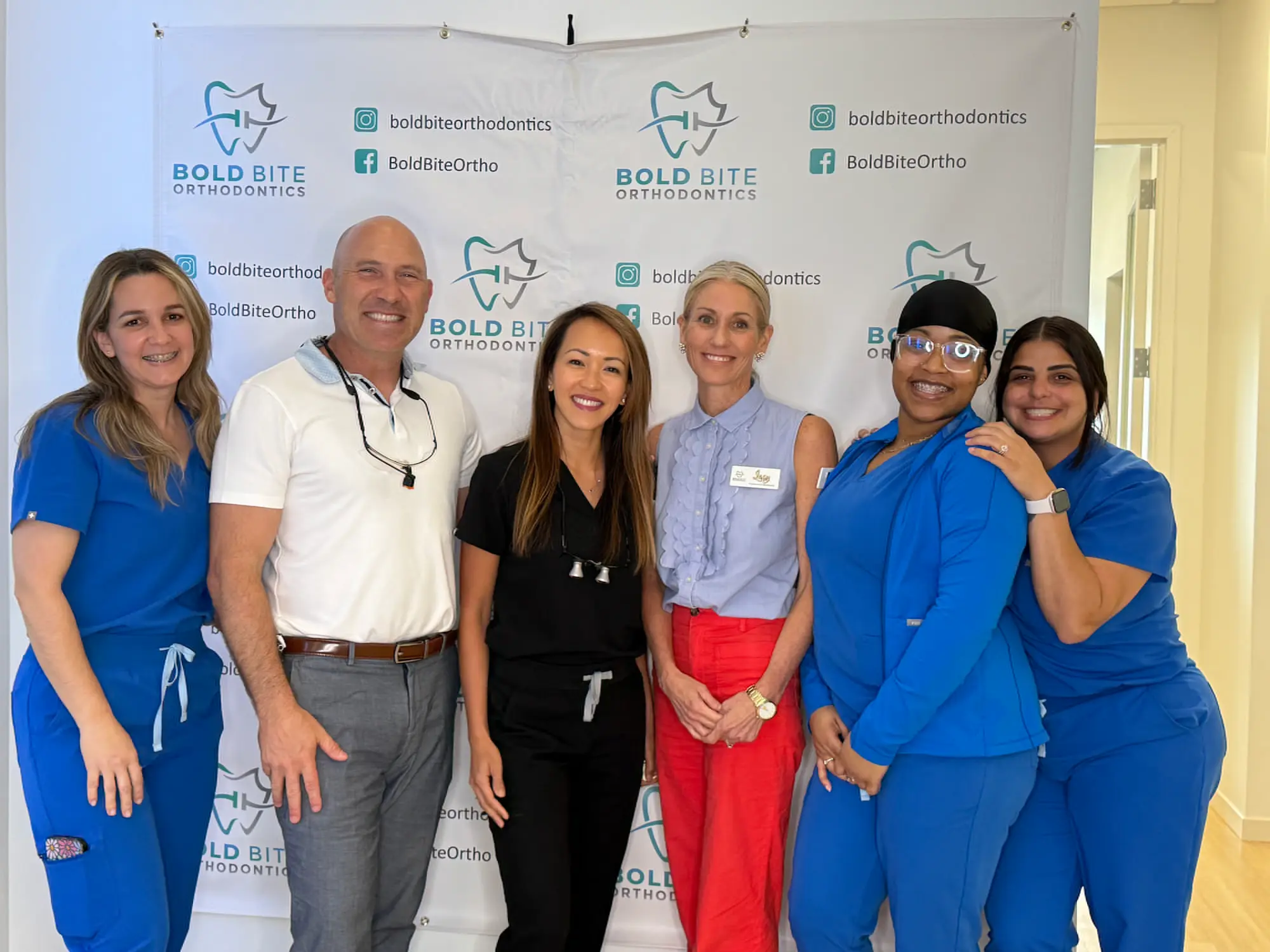 Dr. Marty Greenberg, Dr. Trang Cao, and their orthodontics team pose in front of a Bold Bite Orthodontics in Jacksonville, FL.