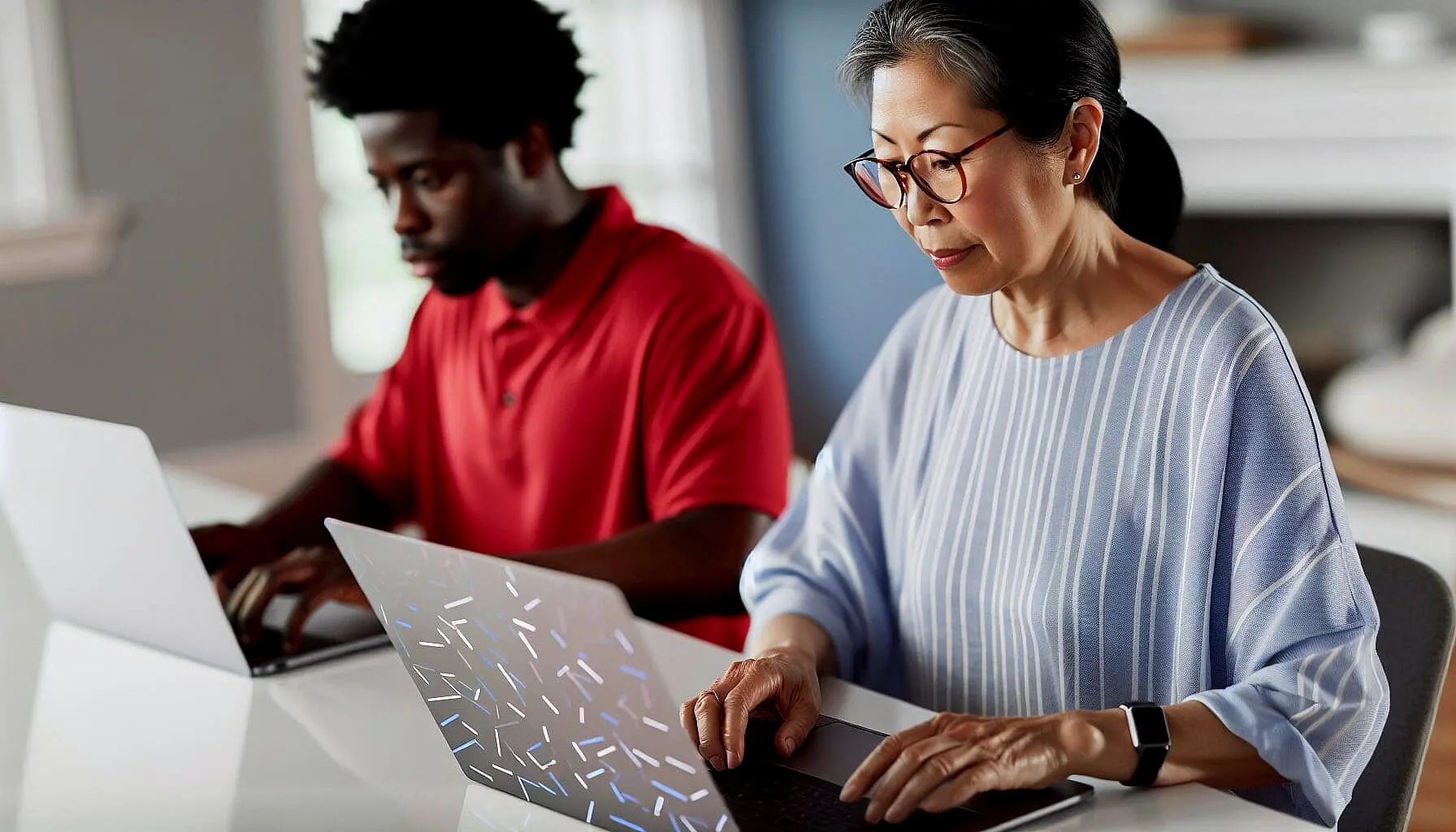 Two people sit side by side at a table, each working on a laptop computer in a well-lit room, discussing topics like affordable braces in Jacksonville, FL.