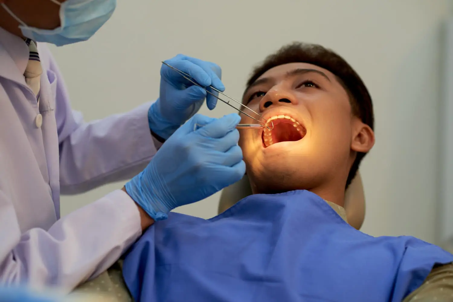 In Jacksonville FL, a dentist wearing gloves and a mask uses dental tools to examine a patient’s mouth for conditions like an underbite while the patient sits in a dental chair.