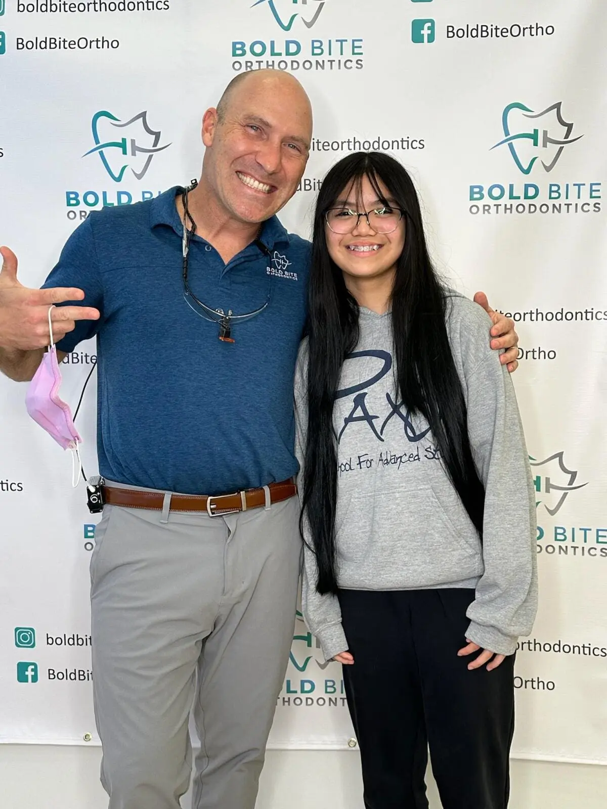 Dr. Marty Greenberg and a young patient stand side by side, smiling, in front of a Bold Bite Orthodontics in Jacksonville, FL.