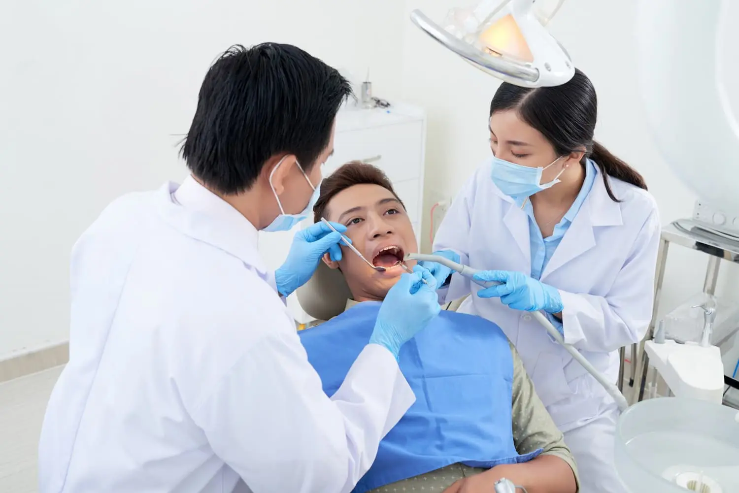 A dentist and dental assistant in masks and gloves perform a dental procedure addressing tongue thrust: diagnosis and treatment in Jacksonville FL, ensuring expert care in a clinic setting.