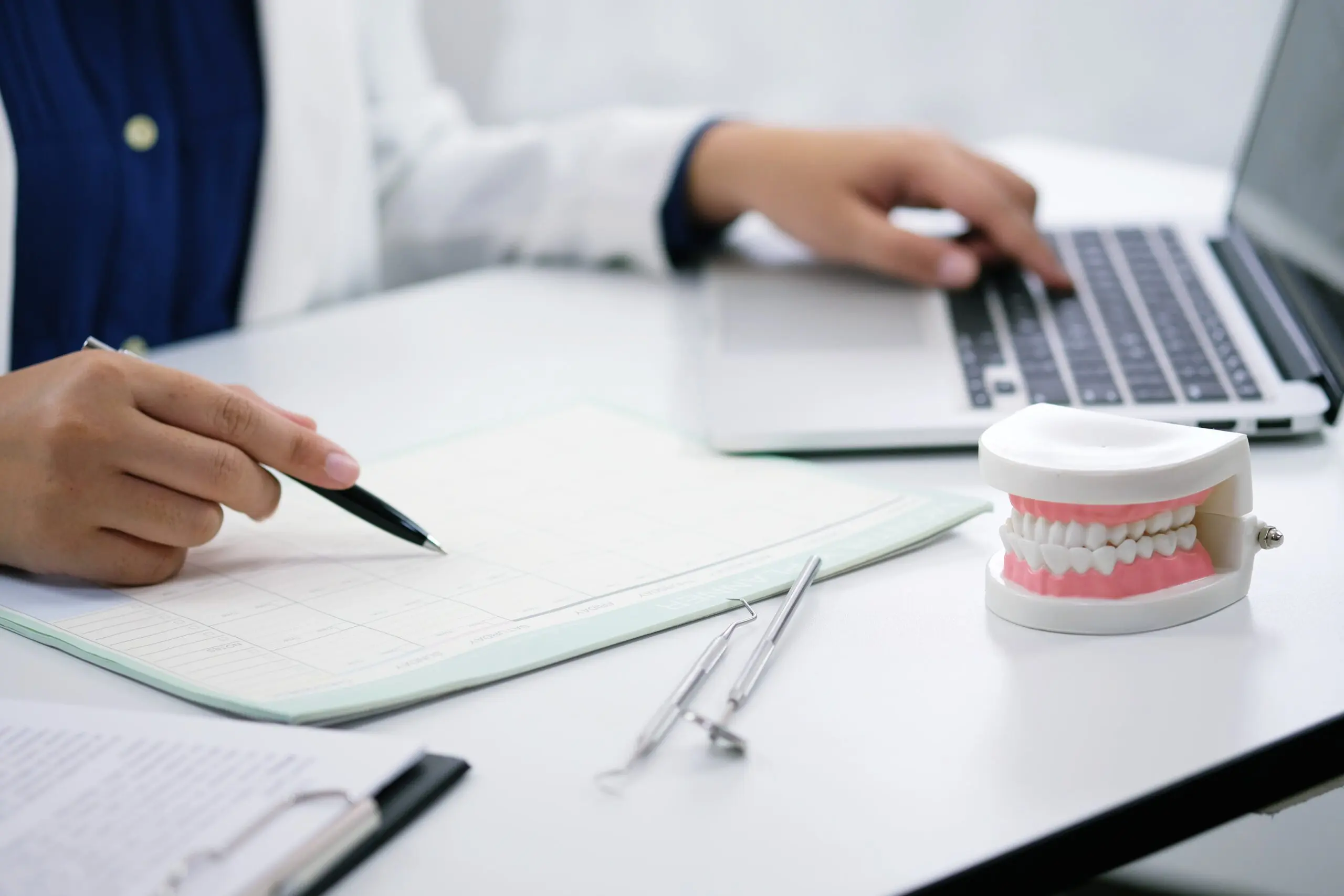 Person working at a desk with a laptop, dental model, dental tools, and documents—perhaps planning appointments for Herbst Appliance in Jacksonville FL.