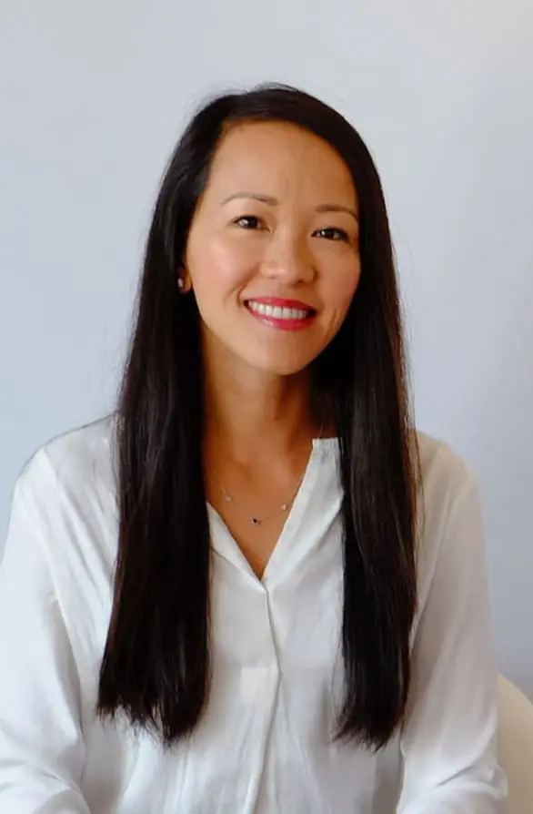 Rodrigo F. Viecilli: Orthodontist in Austin TX Trang Cao, with long dark hair, smiles in a white blouse before a light background at Bold Bite Orthodontics in Jacksonville, FL.