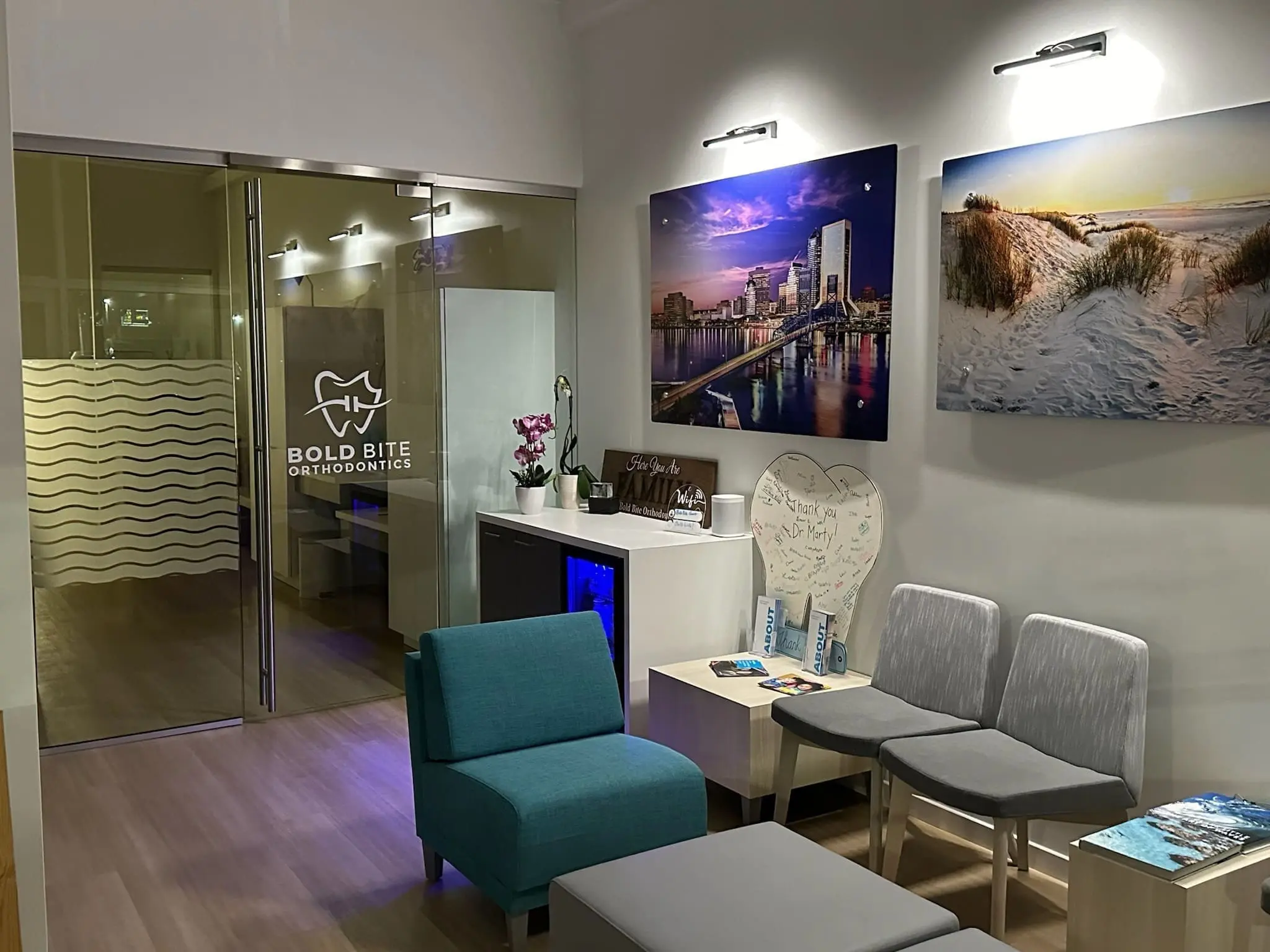 Bold Bite Orthodontics serves Patton Park families from the Bold Bite Orthodontics office in Jacksonville, FL features blue and gray chairs, wall art, brochures, and a glass door with the practice’s name.